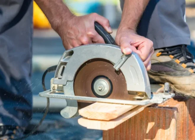 Handheld circular saw cutting wood on a construction site