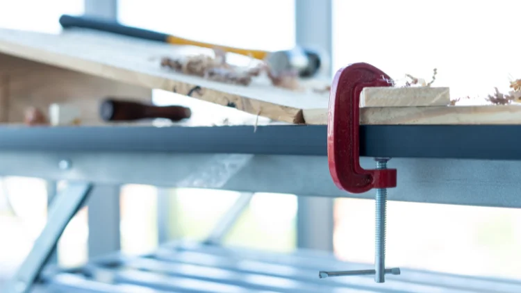 Securing wood with a red C-clamp.
